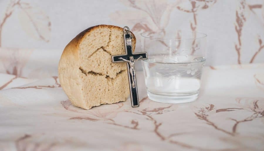 Crucifix pendant on bread beside glass