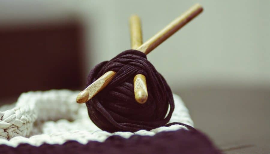 brown yarn roll with two brown crochet hooks on top of white surface