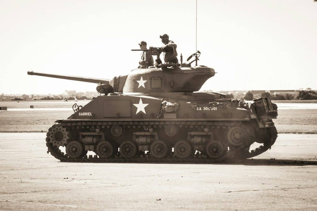 two people riding on battle tank