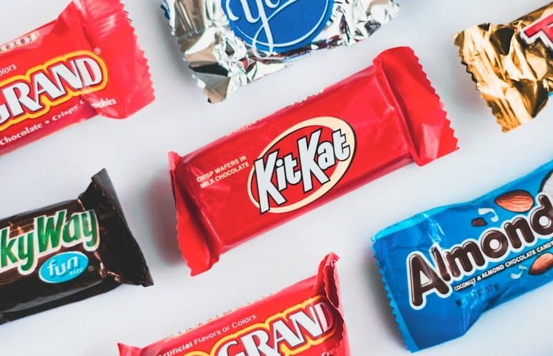 a variety of candy bars lined up on a white surface