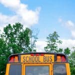 school bus near green trees under cloudy sky during daytime